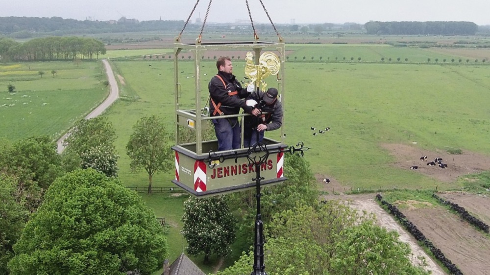 Plaatsing van de gerestaureerde windvaan-haan met hoogwerker in Persingen